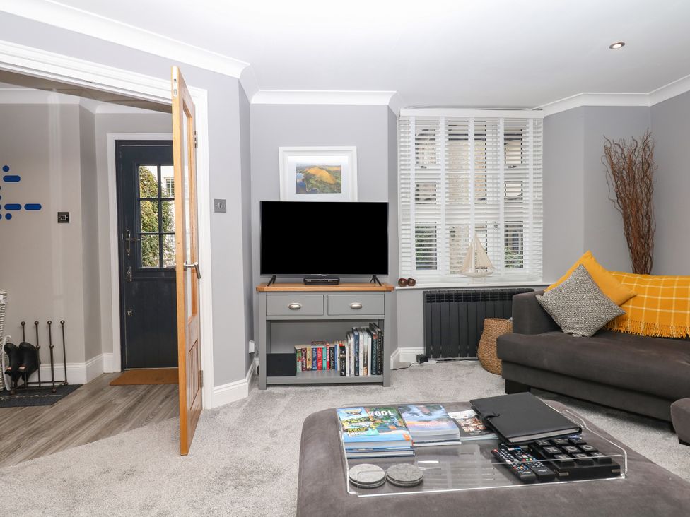 A living room with a television and sofa at 12 Courtyard Cottage at Sheplegh Court Totnes