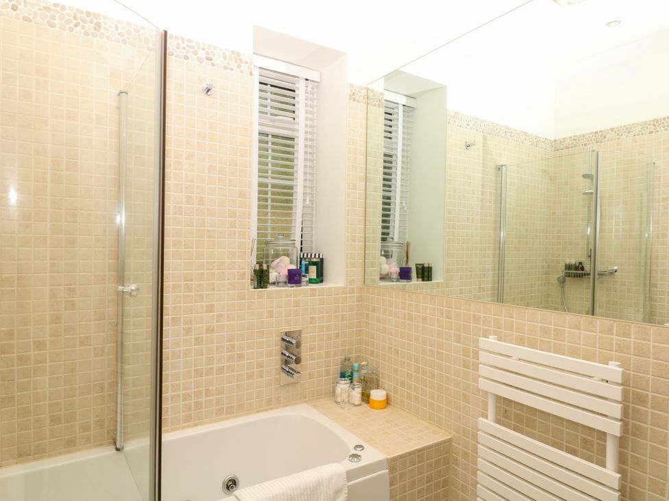 A bathroom with a shower and bath at 12 Courtyard Cottage at Sheplegh Court Totnes
