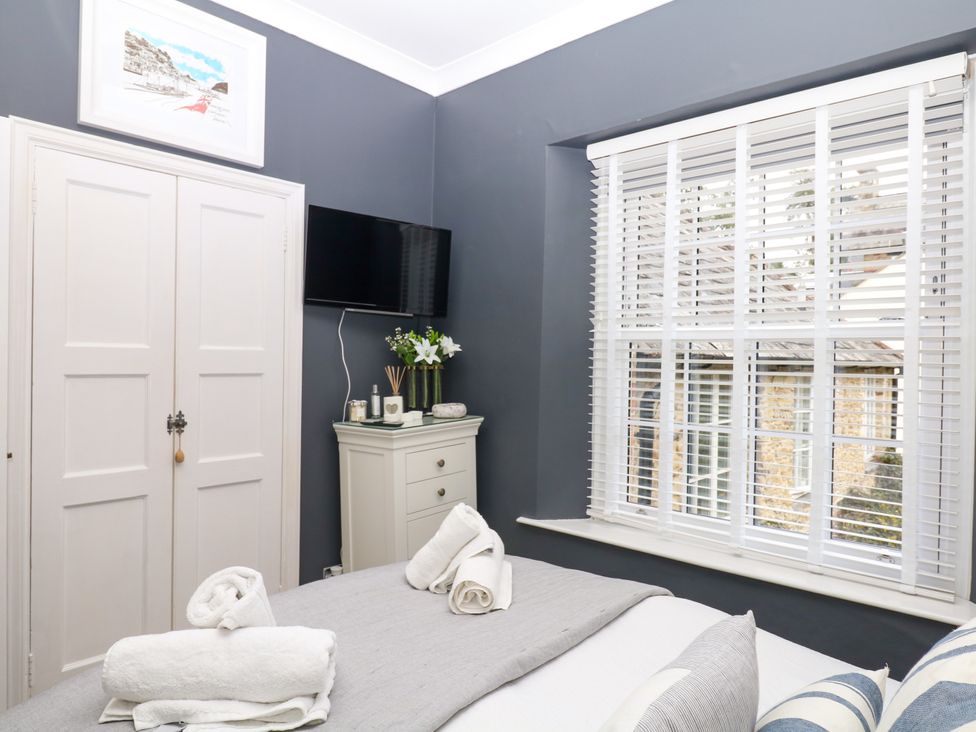 A bedroom with a bed and wardrobe at 12 Courtyard Cottage at Sheplegh Court in Totnes
