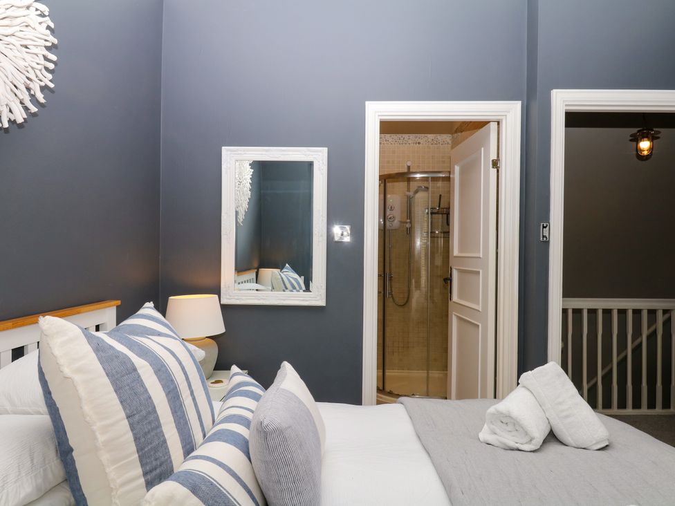 A bedroom with a bed, mirror, and an adjoining bathroom at 12 Courtyard Cottage at Sheplegh Court in Totnes
