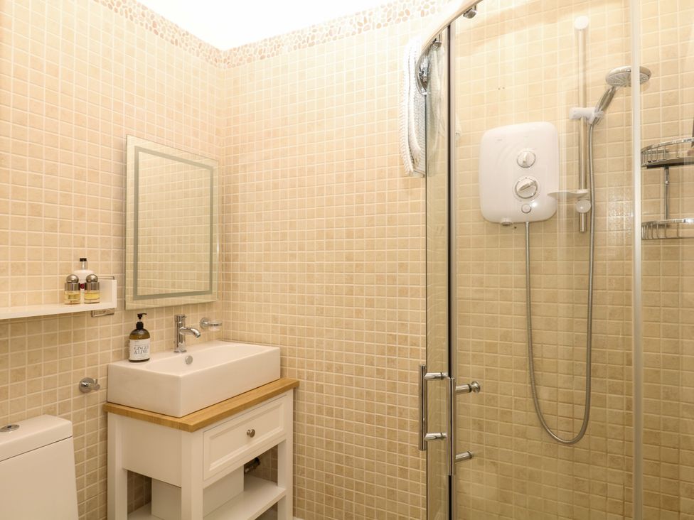 A bathroom with a shower and sink at 12 Courtyard Cottage at Sheplegh Court Totnes