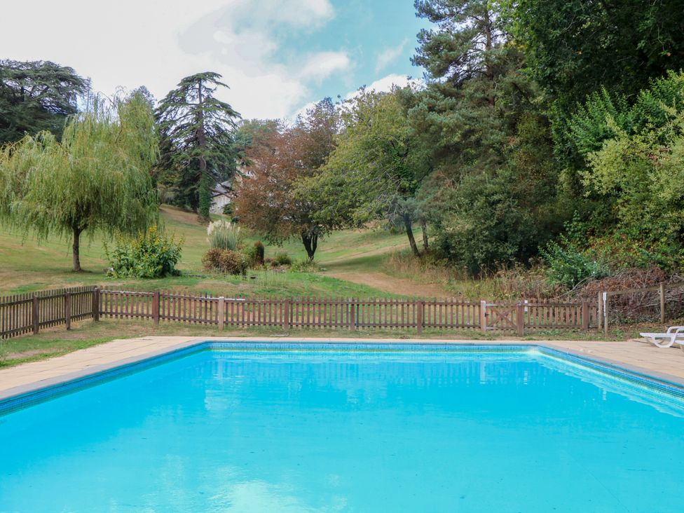 An outdoor area with a swimming pool and surrounding grass at 12 Courtyard Cottage at Sheplegh Court in Totnes