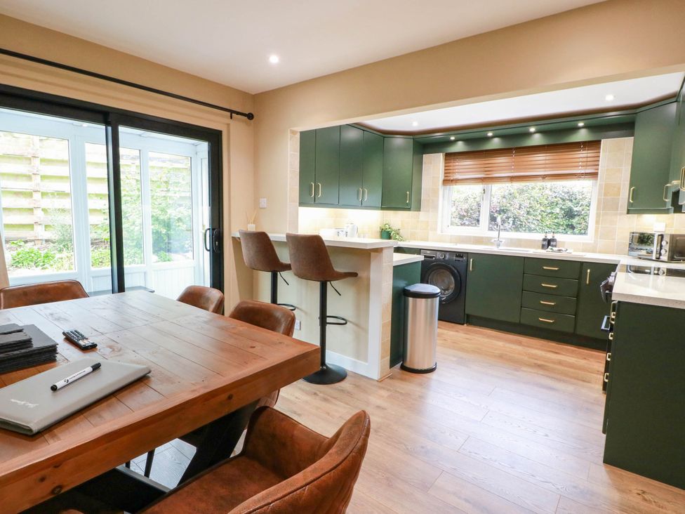A kitchen with a dining table and bar stools at Camusfearna in Dalbeattie