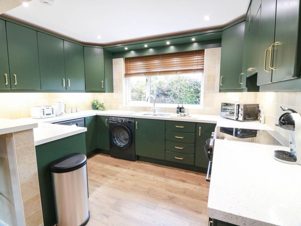 A kitchen with cabinets, sink, washing machine, and appliances at Camusfearna in Dalbeattie