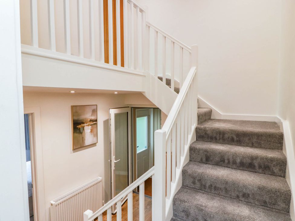 A staircase with a handrail and door at Camusfearna in Dalbeattie
