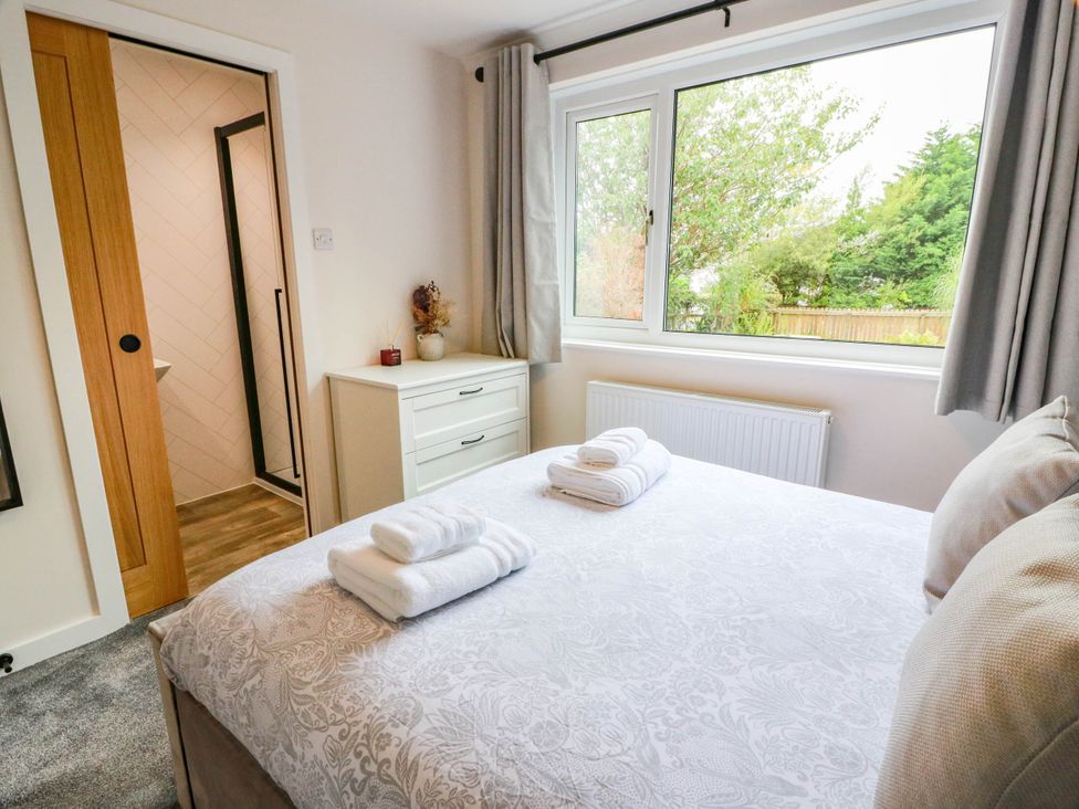 A bedroom with a bed, dresser and window at Camusfearna in Dalbeattie