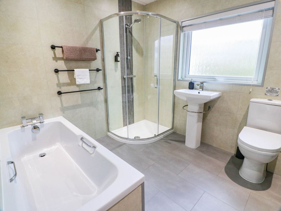 A bathroom with a bathtub, shower, and sink at Camusfearna in Dalbeattie