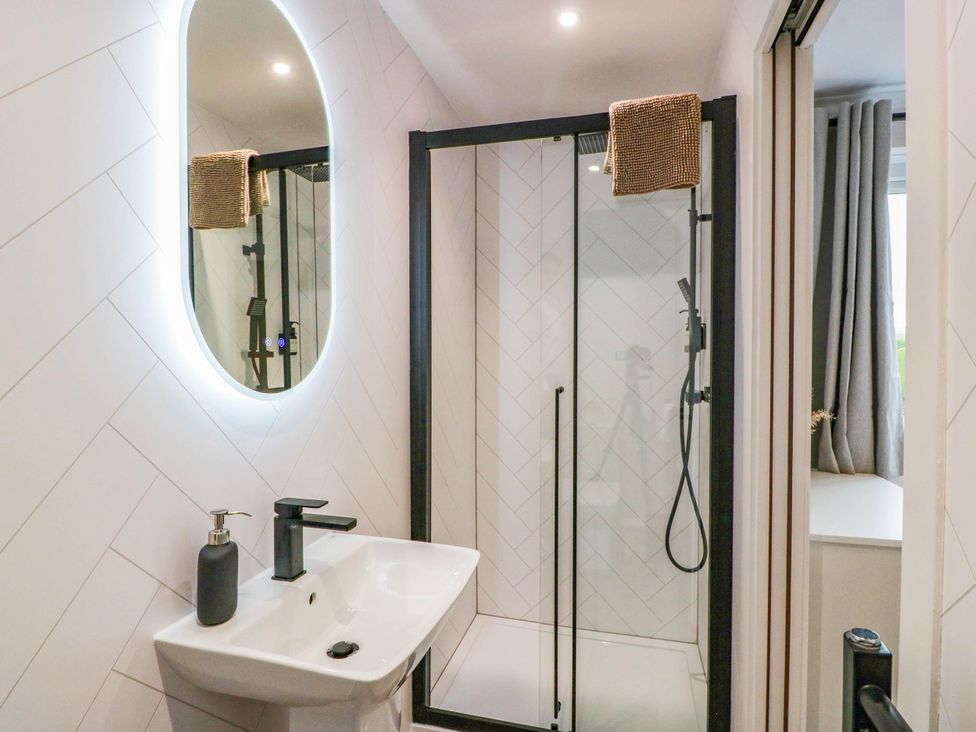 A bathroom featuring a sink, mirror, and shower at Camusfearna in Dalbeattie