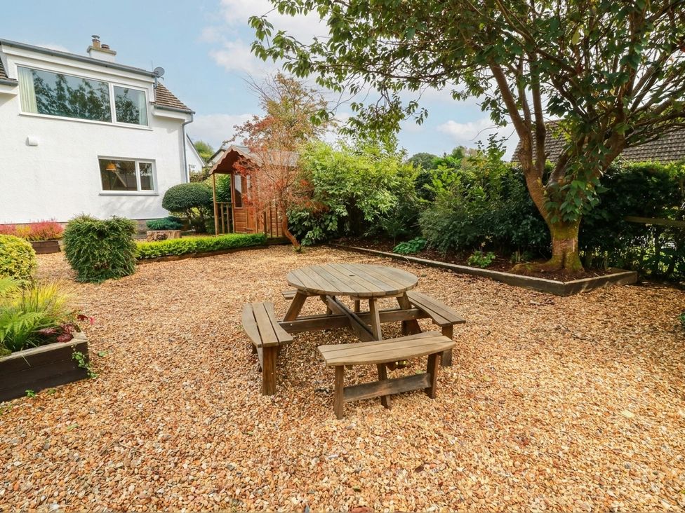 A garden with a wooden table and benches at Camusfearna in Dalbeattie