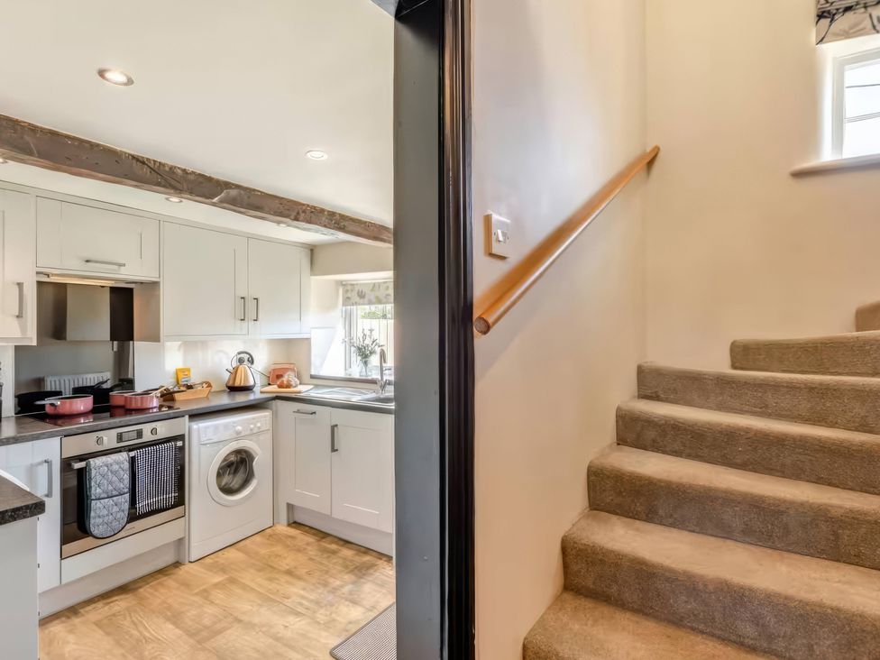 A kitchen with appliances and a staircase at The Quirky Cottage in Eamont Bridge near Ullswater