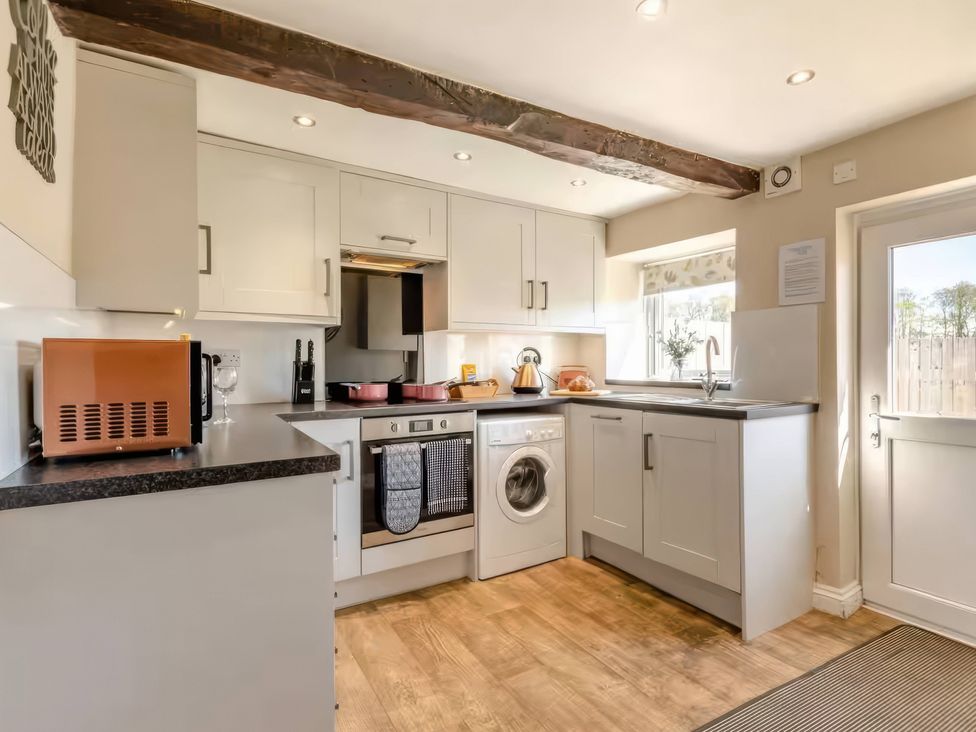 A kitchen with appliances and a window at The Quirky Cottage in Eamont Bridge near Ullswater