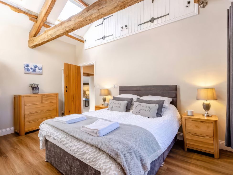 A bedroom featuring a bed with pillows and a bedside table at The Quirky Cottage in Eamont Bridge near Ullswater