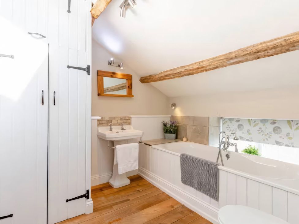 A bathroom with a bathtub and sink at The Quirky Cottage in Eamont Bridge near Ullswater