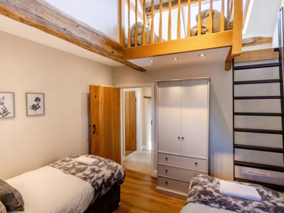 A bedroom with twin beds and a staircase at The Quirky Cottage near Eamont Bridge