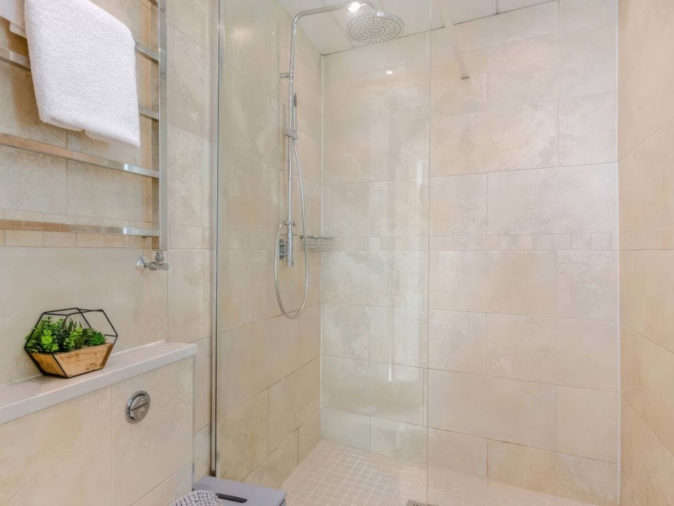 A shower area with towel rack and plant at The Quirky Cottage Eamont Bridge near Ullswater