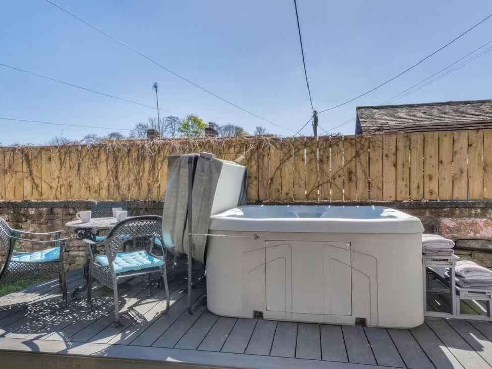 An outdoor area with a hot tub and chairs at The Quirky Cottage Eamont Bridge near Ullswater