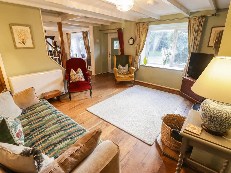 A living room with a sofa, armchair, and coffee table at Ty'r Wennol in Fishguard