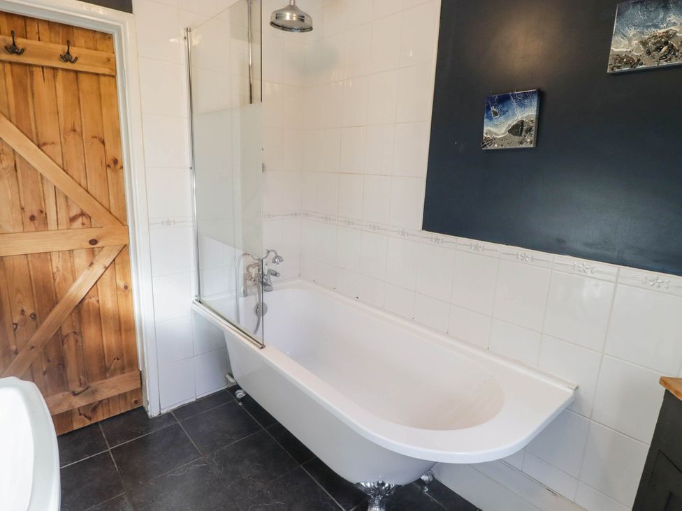 A bathroom featuring a bathtub with shower at Ty'r Wennol in Fishguard
