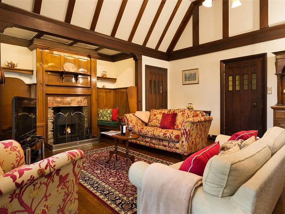 A living room with a fireplace and seating at White Gables in Ambleside