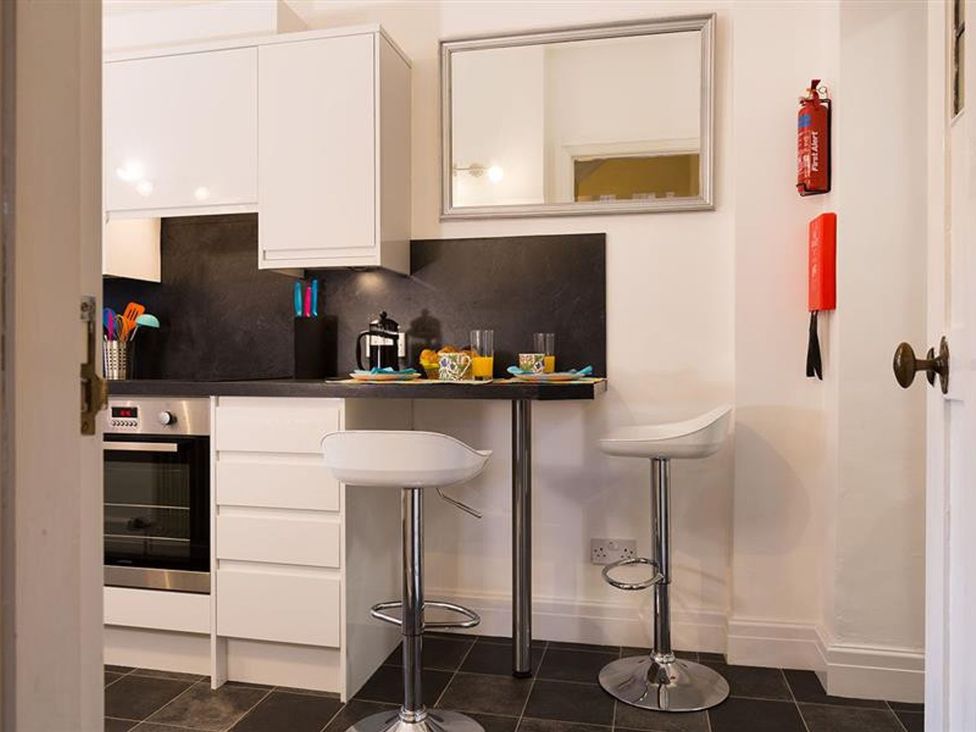 A kitchen with a table and stools at White Gables in Ambleside