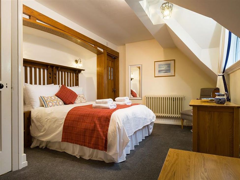 A bedroom with a bed and dresser at White Gables in Ambleside