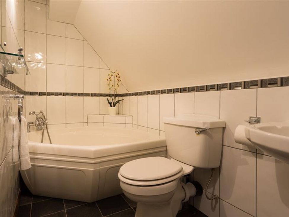A bathroom with a bathtub, toilet and sink at White Gables in Ambleside
