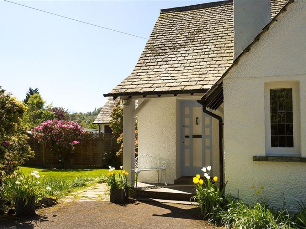 A house entrance with a bench and flower pots at White Gables in Ambleside