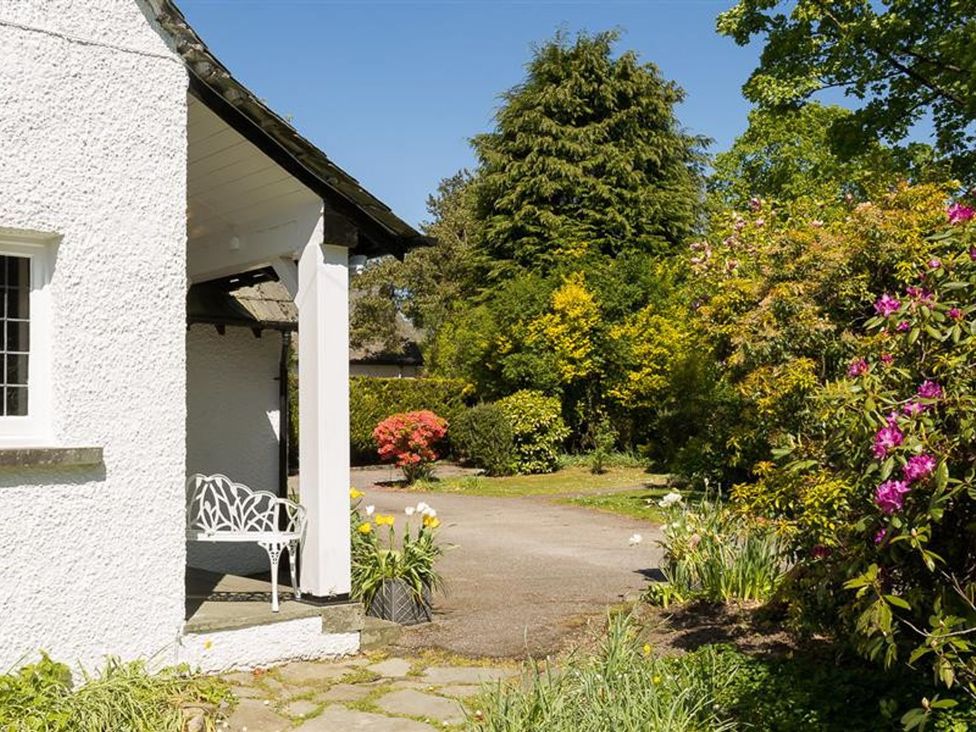 A garden with flowers and a bench at White Gables in Ambleside