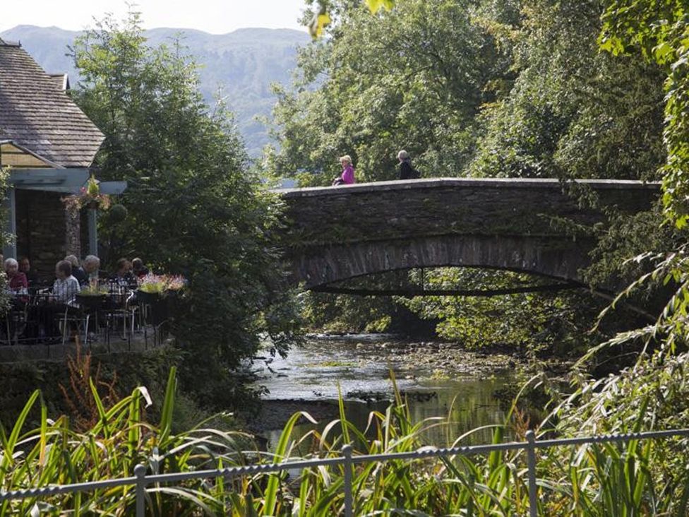 A bridge over a river with people walking at White Gables in Ambleside