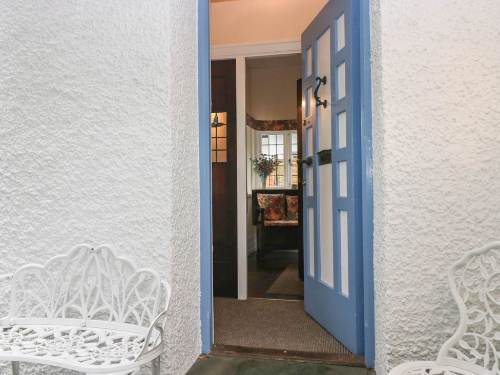 An entrance with a blue door and a white bench at White Gables in Grasmere