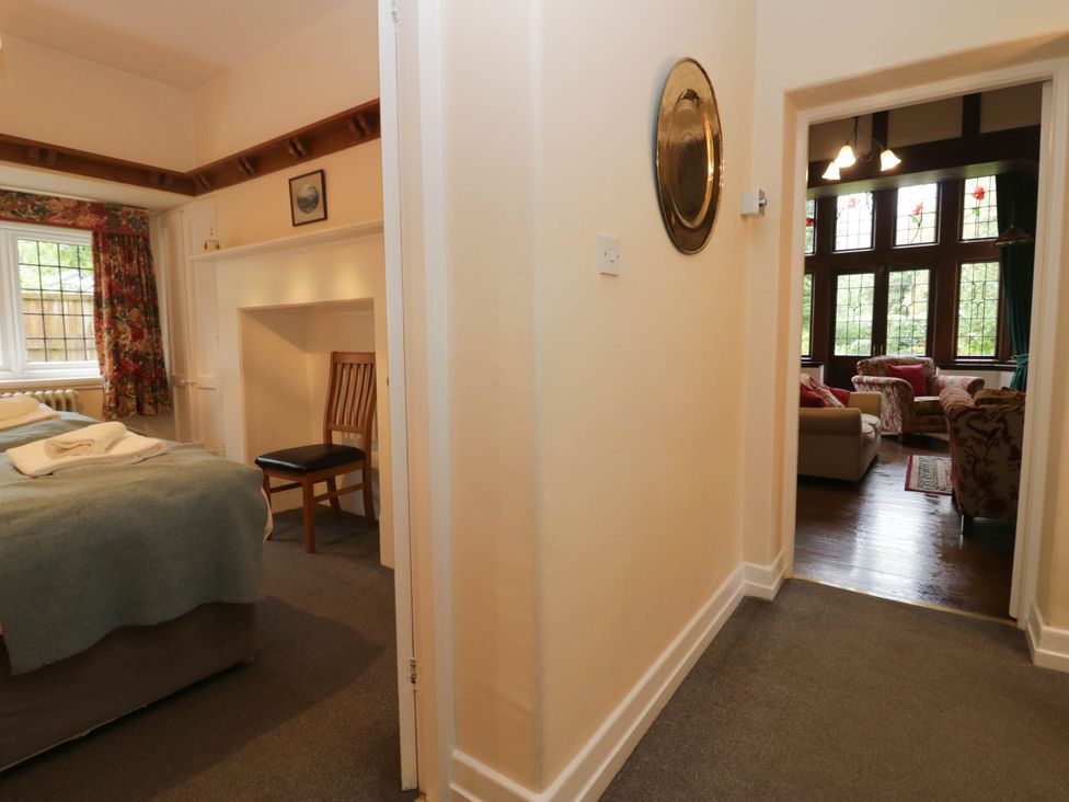 A bedroom with a bed and chair leading to a living room at White Gables Grasmere