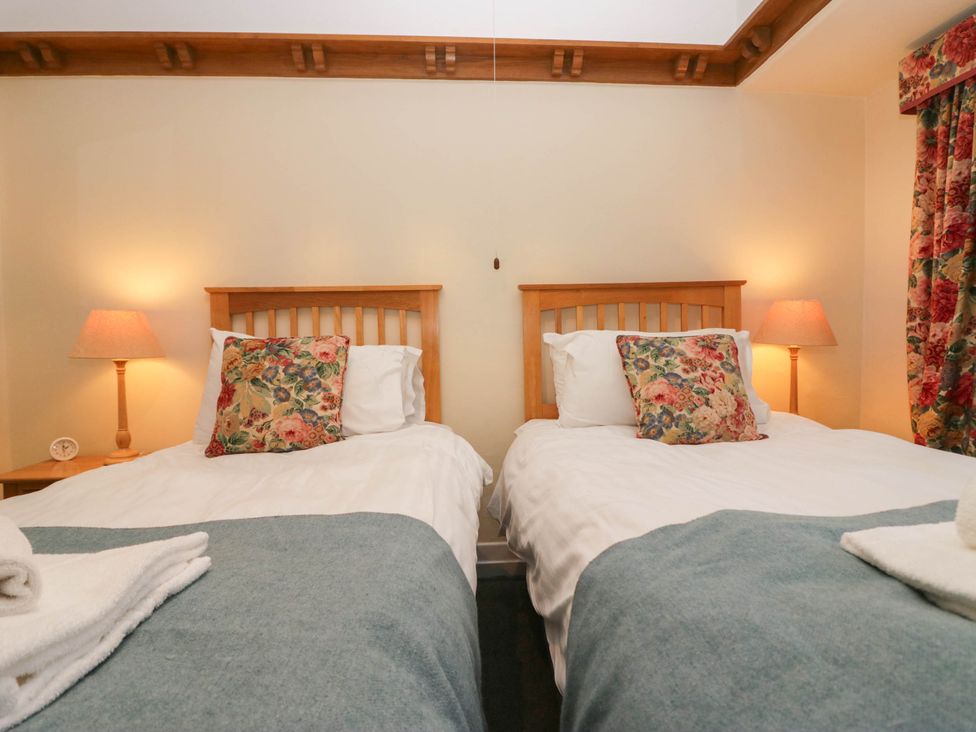 A bedroom with two beds and a lamp at White Gables in Grasmere