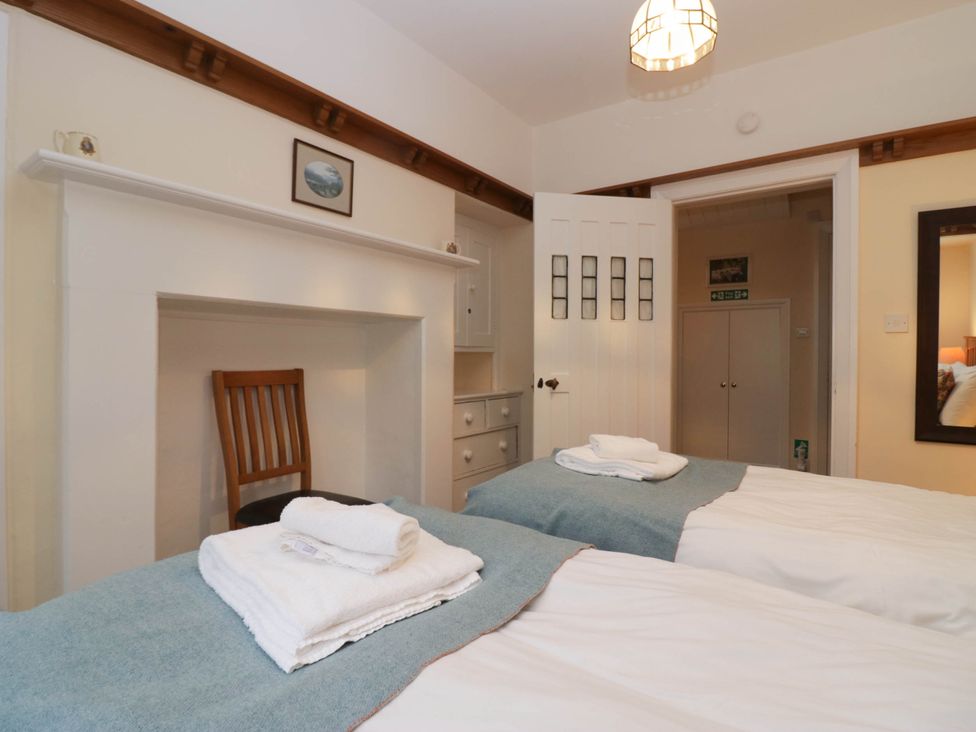 A bedroom with twin beds and a chair at White Gables in Grasmere