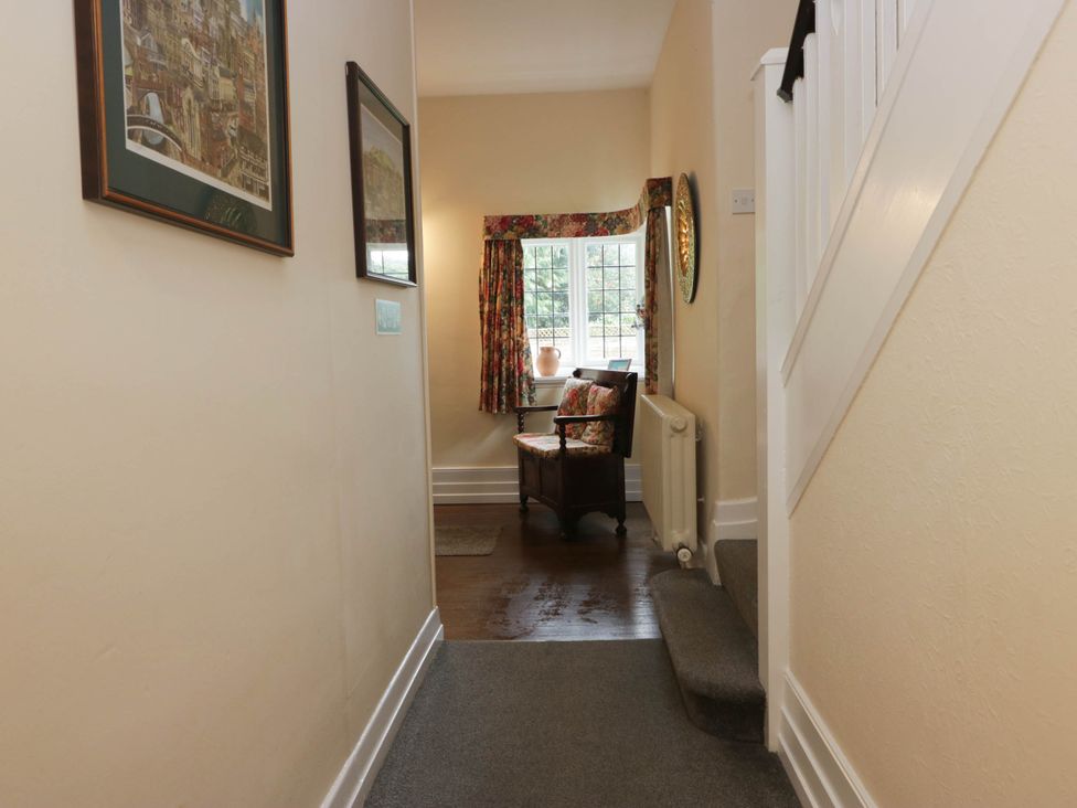 A hallway with framed pictures and a chair at White Gables in Grasmere