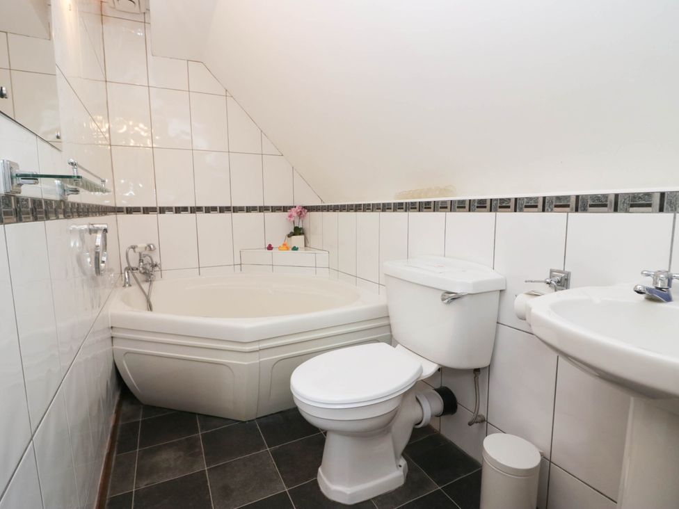 A bathroom with a bathtub, toilet, and sink at White Gables in Grasmere