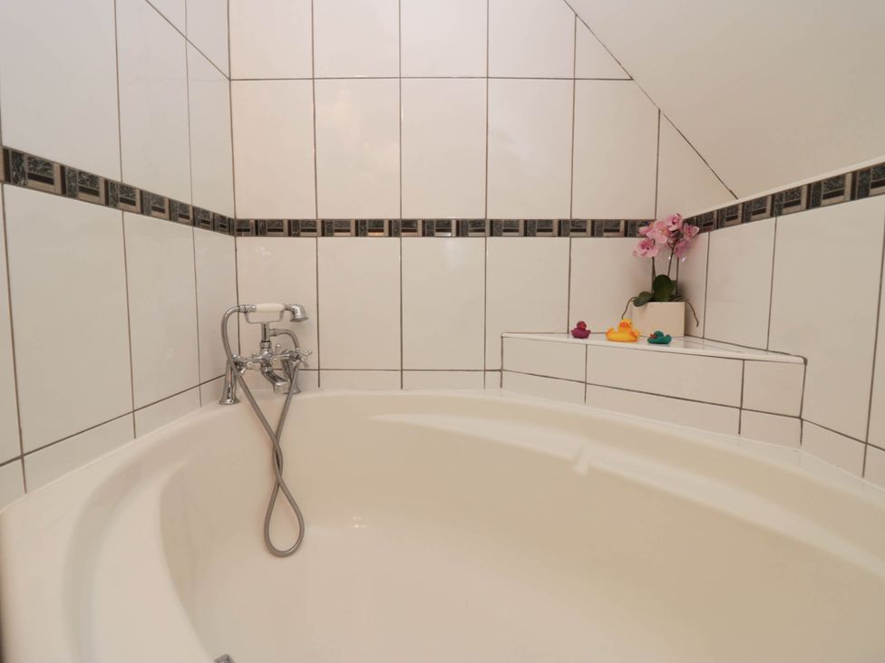 A bathroom with a bathtub and faucets at White Gables in Grasmere