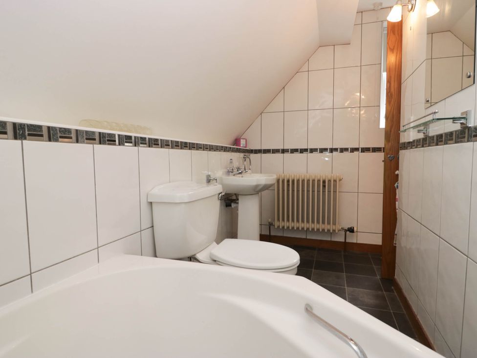 A bathroom with a bathtub, toilet, sink, and radiator at White Gables in Grasmere