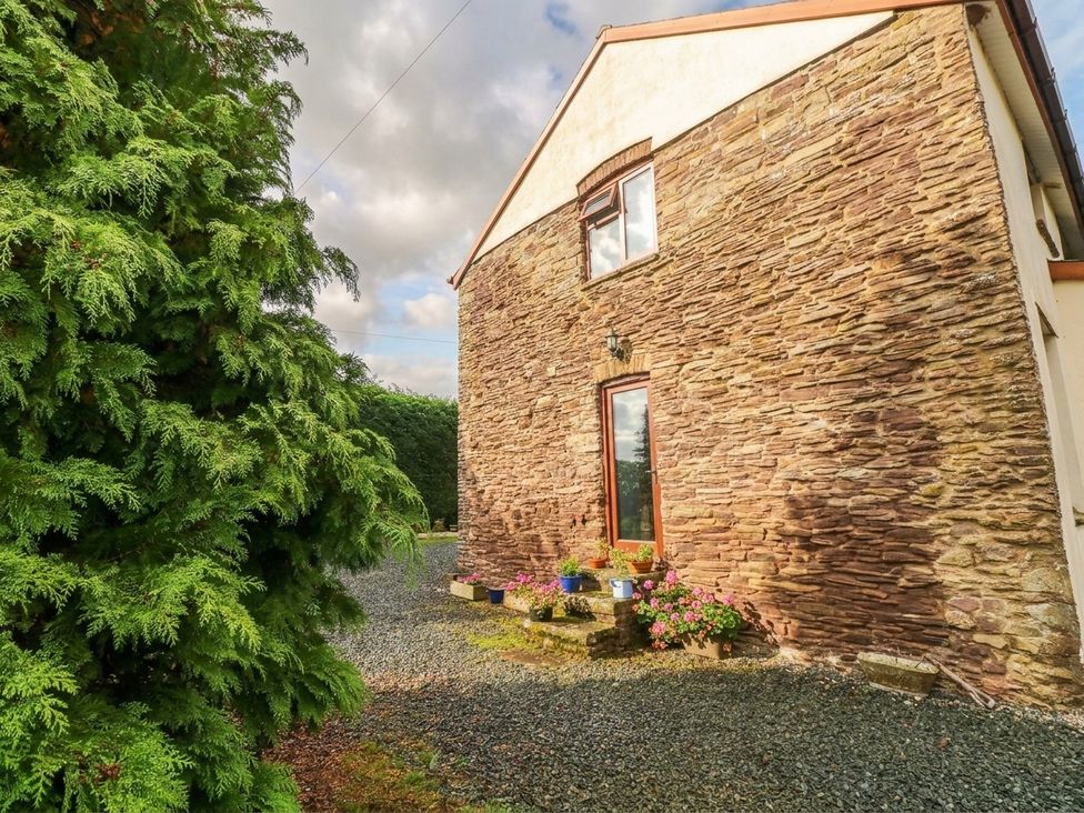 A building with stone exterior and flower pots at Greig House Farm Abergavenny