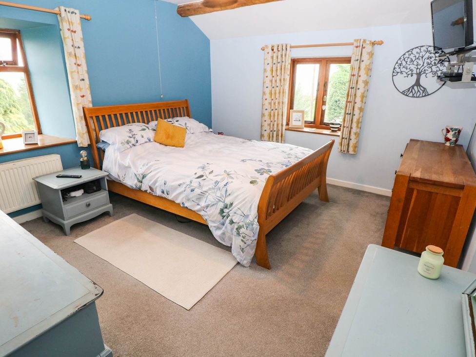 A bedroom with a wooden bed and window at Greig House Farm in Abergavenny