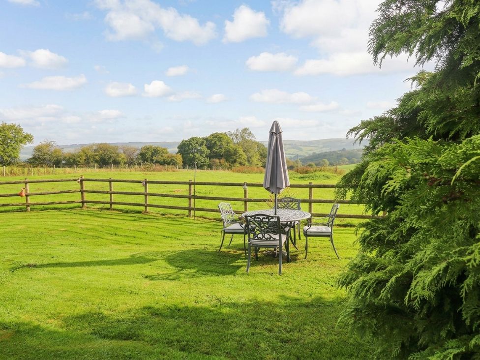 A garden with a table and chairs under an umbrella at Greig House Farm Abergavenny