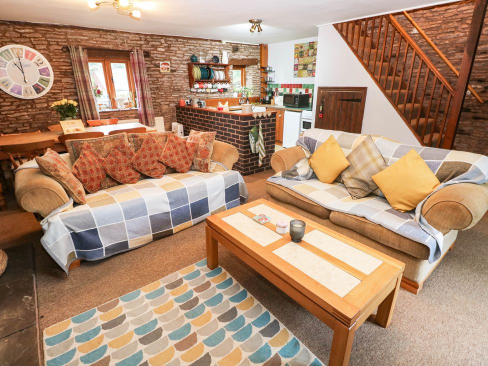 A living room with sofas and a kitchen area at Greig House Cottage Abergavenny