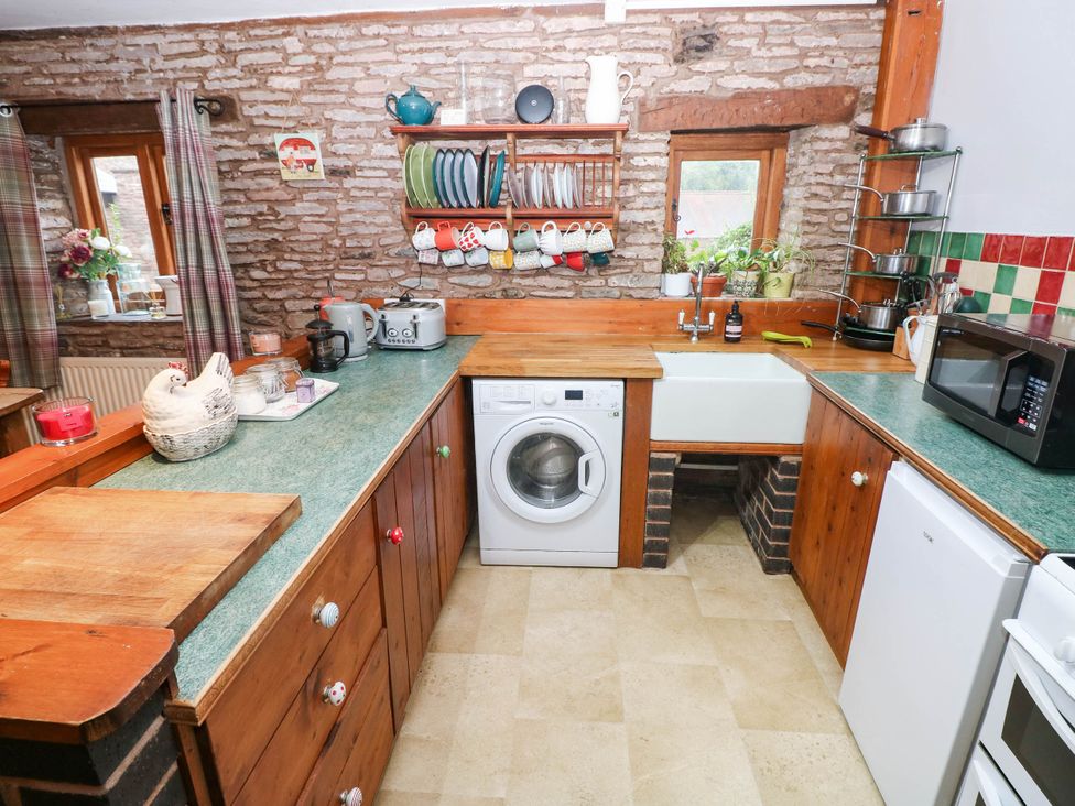A kitchen with wooden cabinets and appliances at Greig House Cottage in Abergavenny