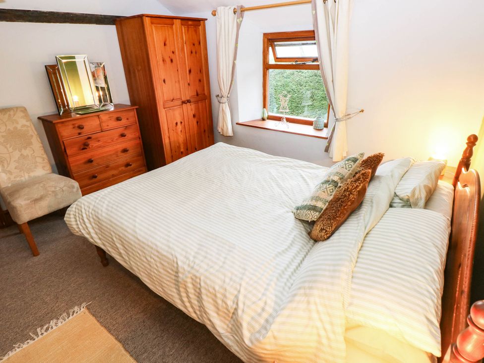 A bedroom with a bed and wooden furniture at Greig House Cottage Abergavenny