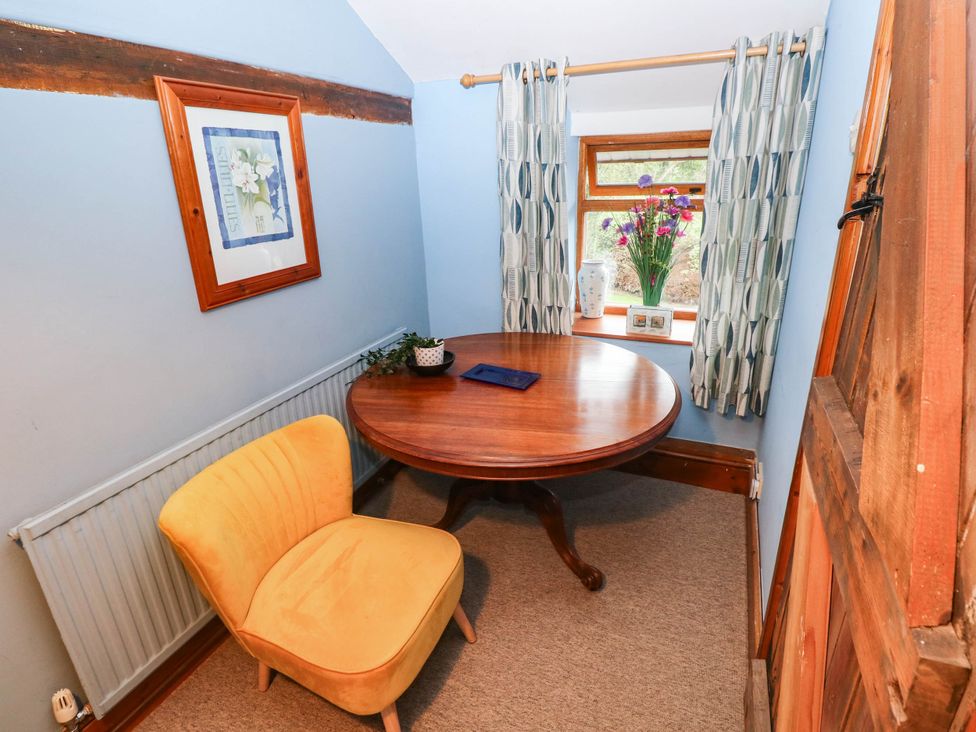 A dining room with a round table and yellow chair at Greig House Cottage Abergavenny