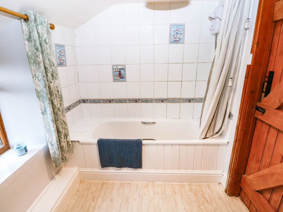 A bathroom with a bathtub and shower curtain at Greig House Cottage Abergavenny