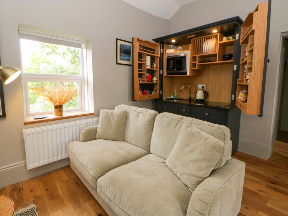 A living room with a sofa and kitchenette at Flat 5 Hereford