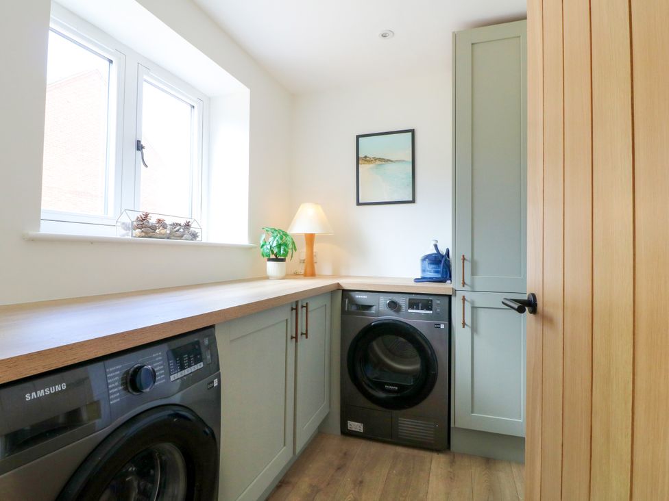 A laundry room with a washing machine and wooden countertop at 7 Forge Close