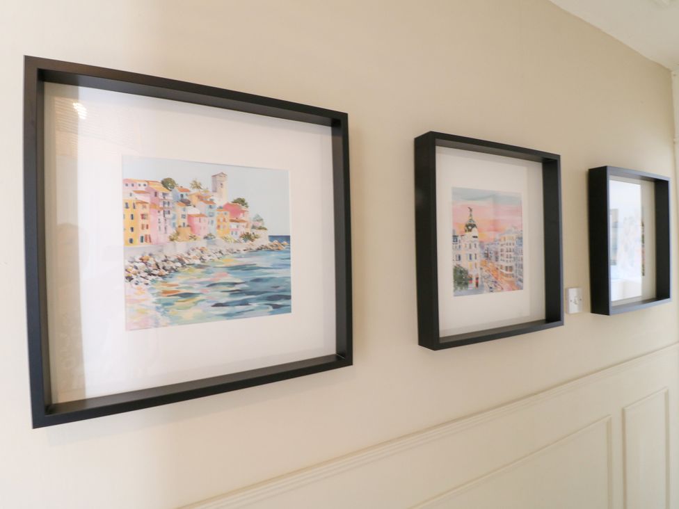 A gallery wall with framed paintings in a hallway at 7 Forge Close