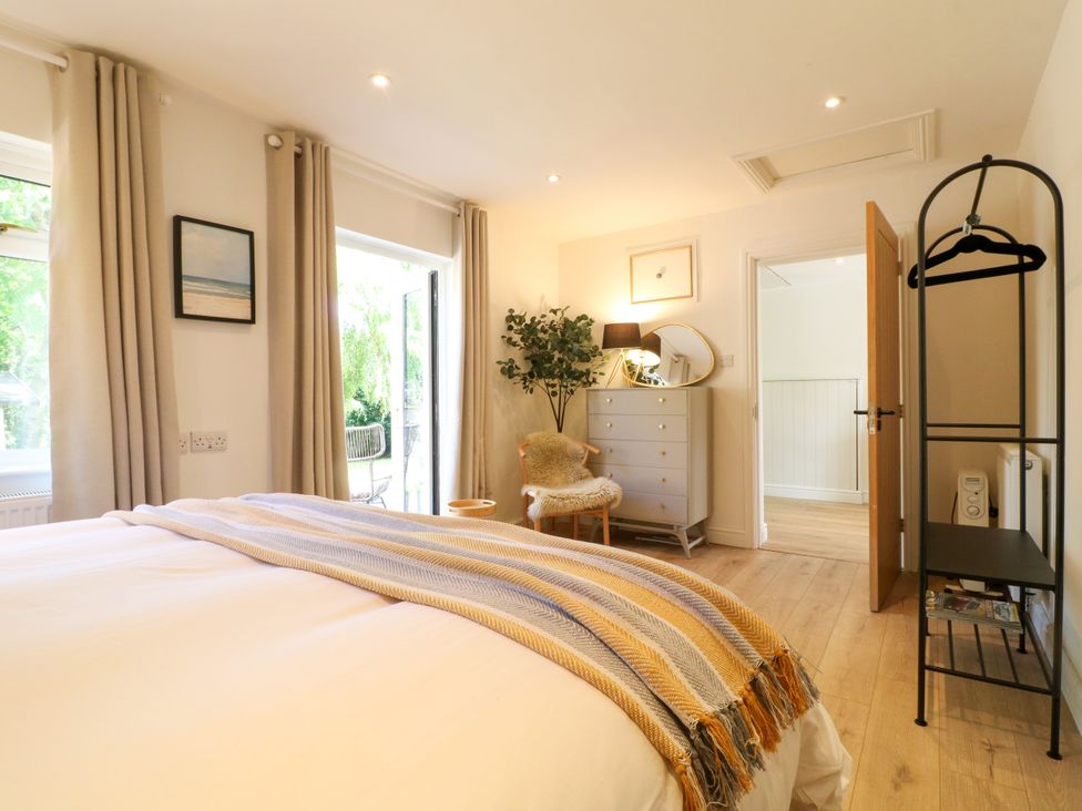 A bedroom with a bed, dresser, and access to an outdoor area at 7 Forge Close
