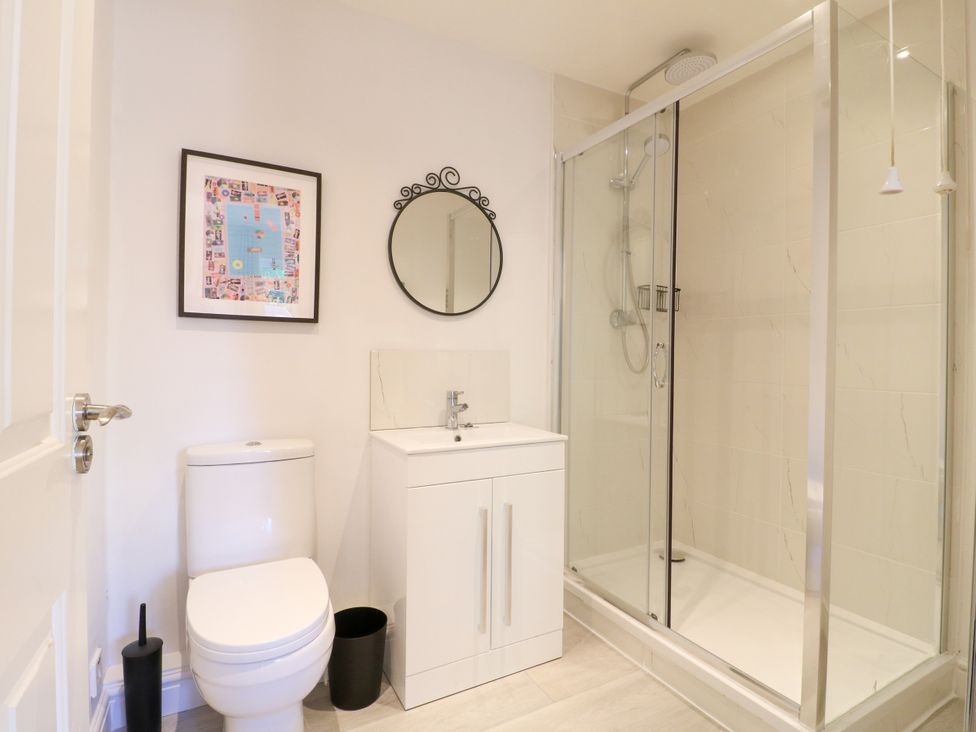 A bathroom with a shower, toilet, sink, and mirror at 7 Forge Close